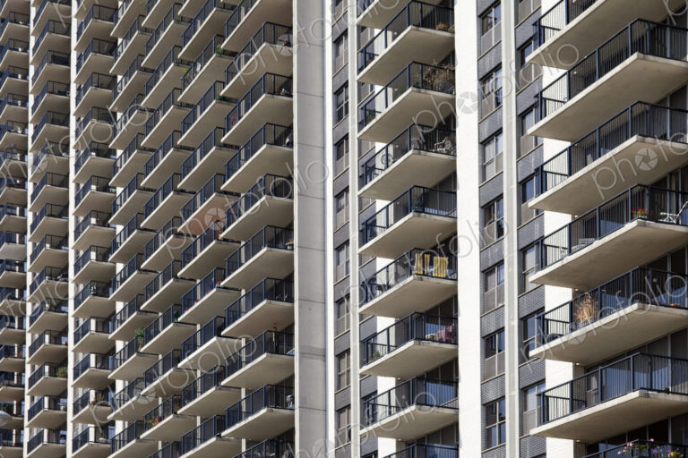 Condominium building exterior, rows of balconies, low angle view.