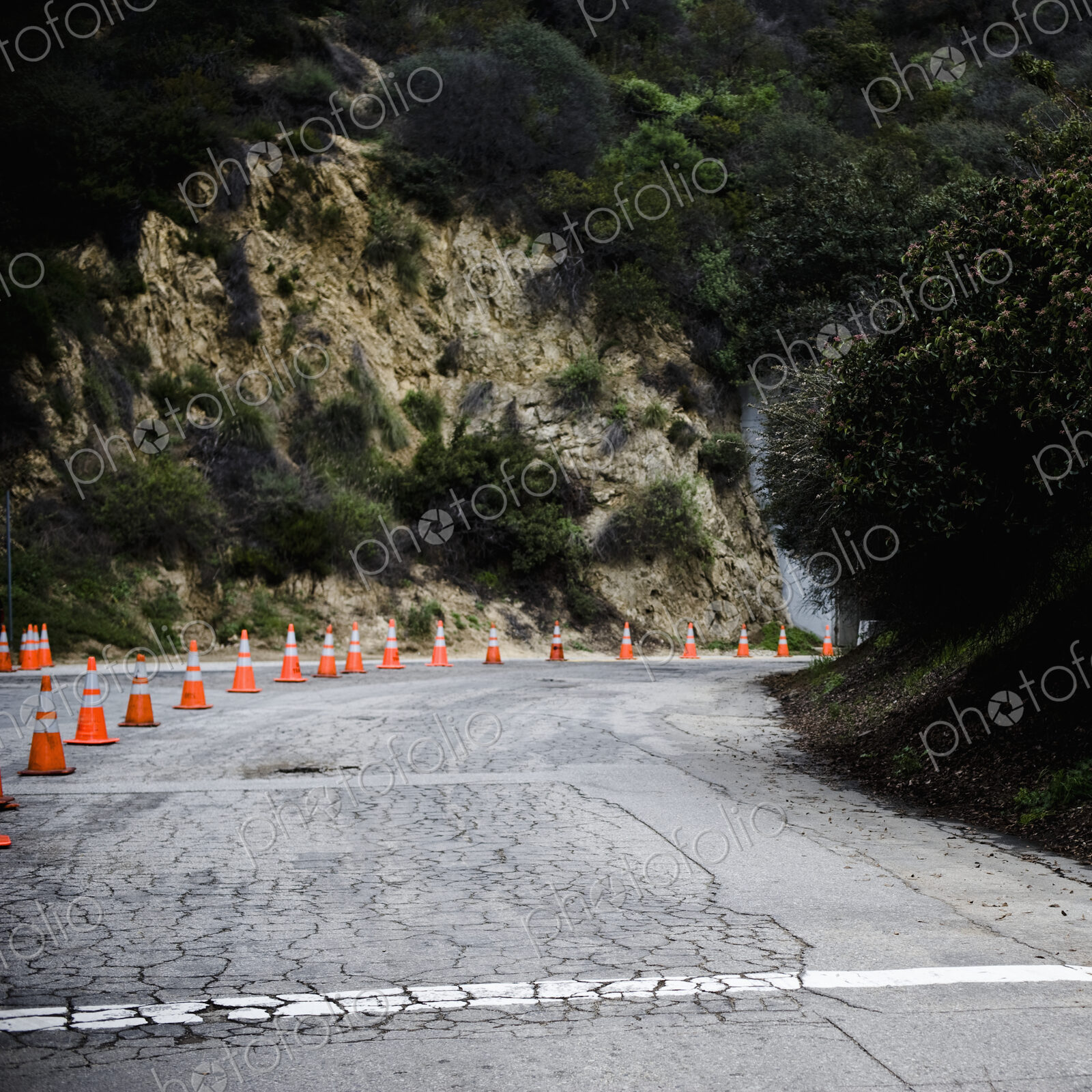 Cones on rural highway with cracked asphalt.
