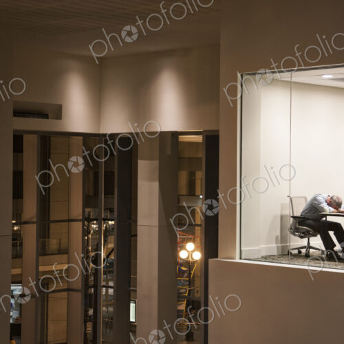 Conference room at night with a single businessman asleep at a conference table. Conference room at night with a single businessman asleep at a conference table.