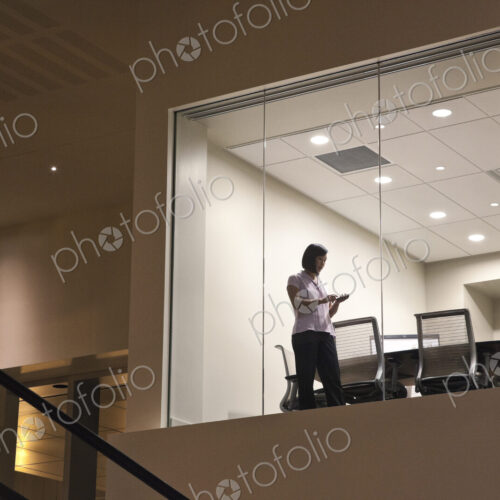 Conference room at night with two business people at work at a conference table.