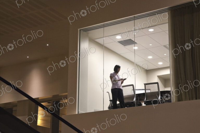 Conference room at night with two business people at work at a conference table.