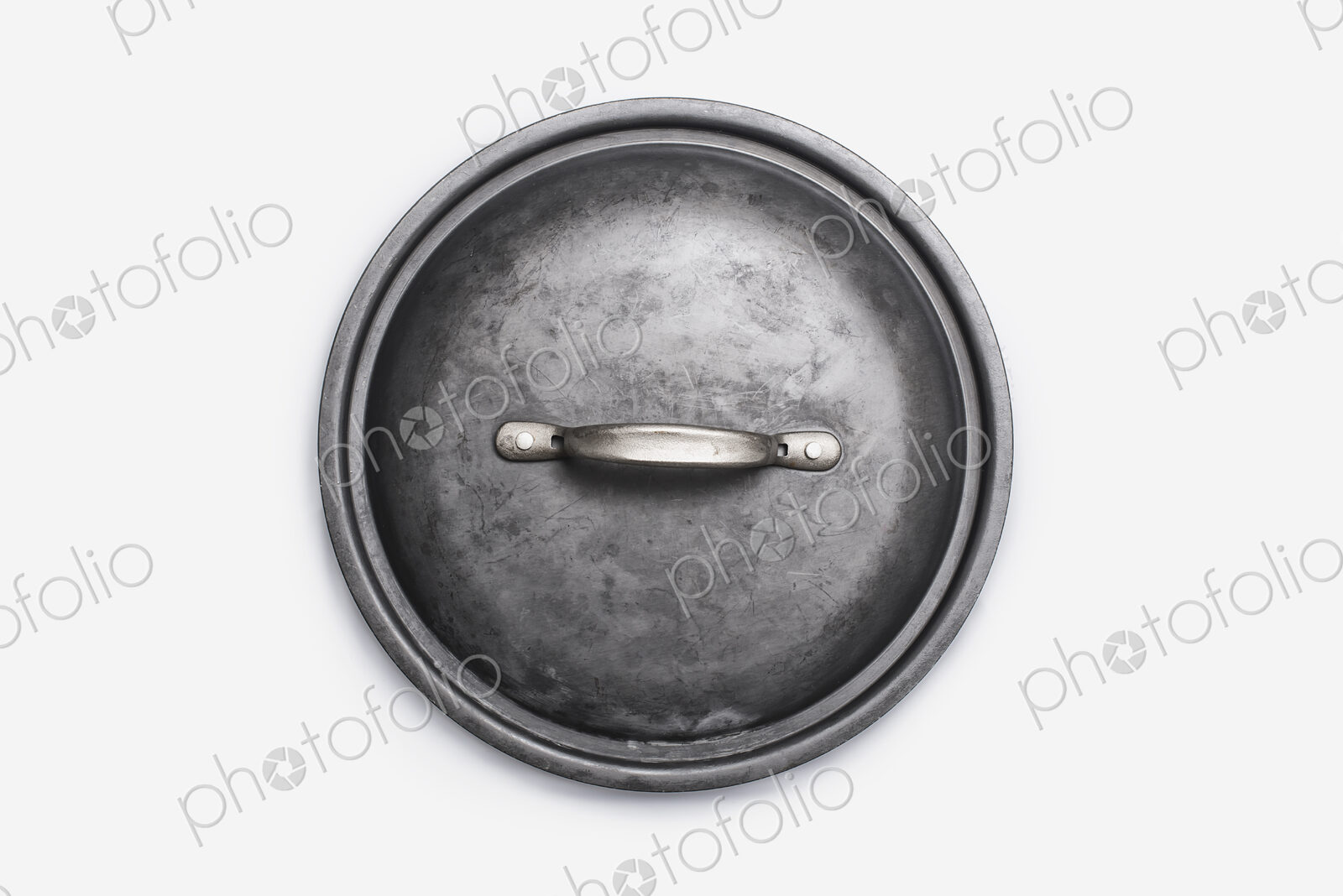 Cookware, a black round pot lid, a well used dented piece of cookware.