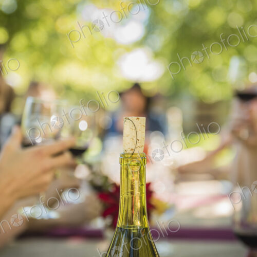 Cork in wine bottle near people drinking wine