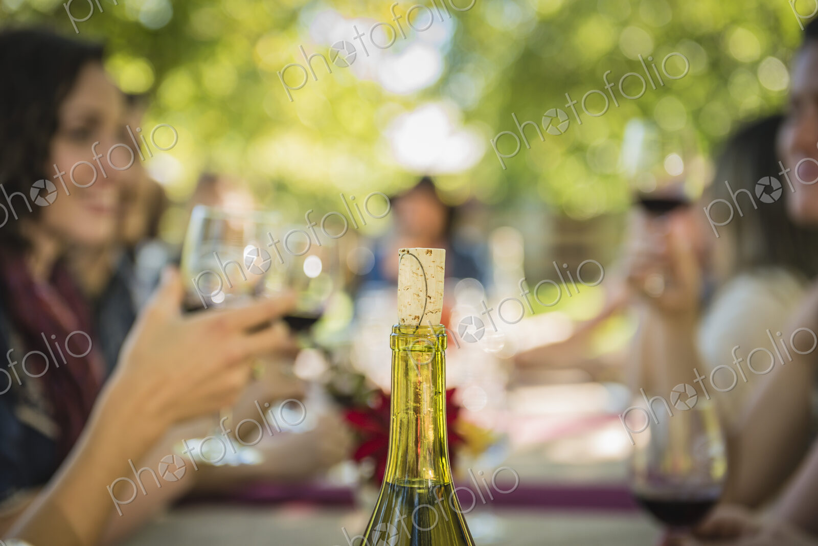Cork in wine bottle near people drinking wine