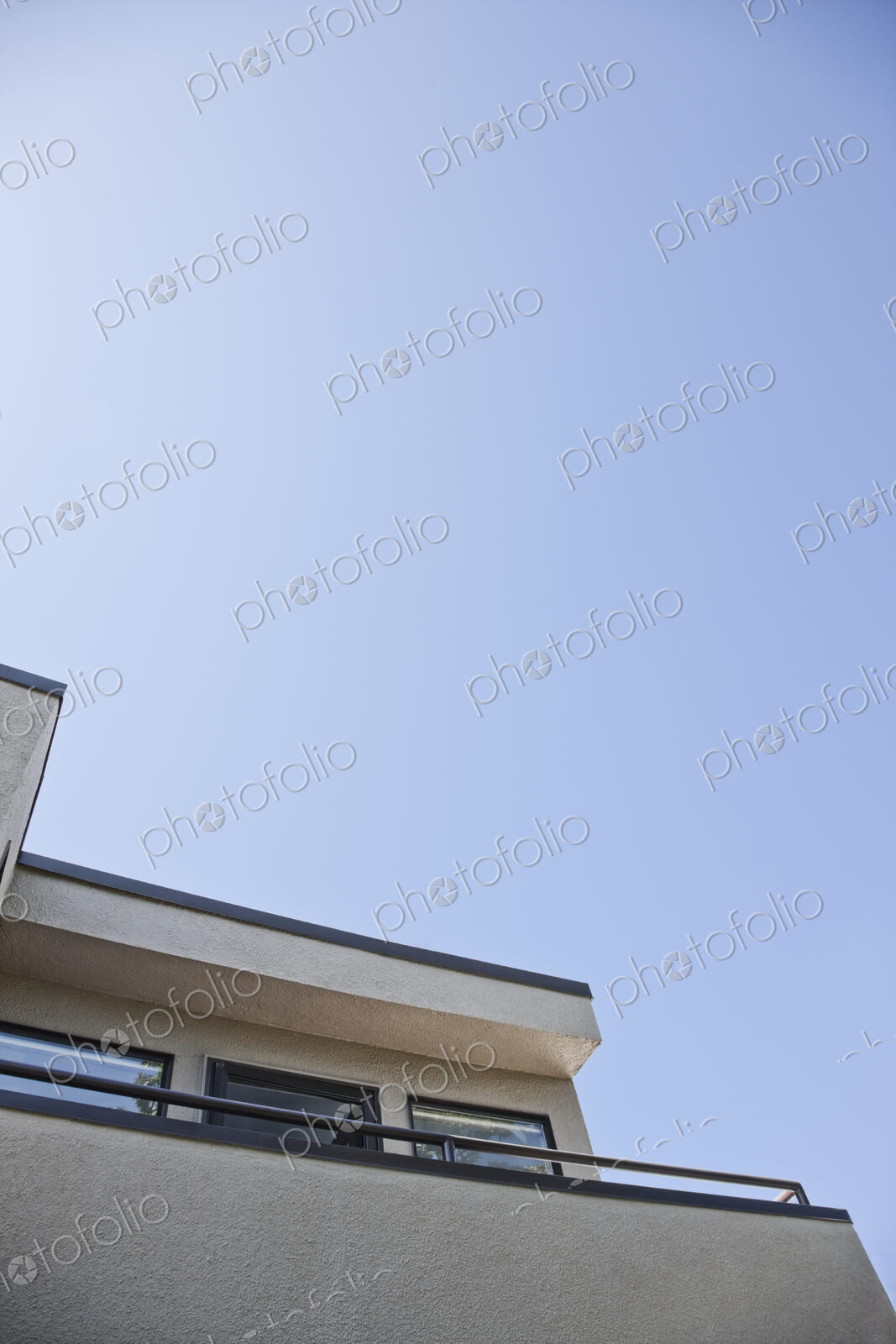 Corner of apartment building and balcony with blue sky.