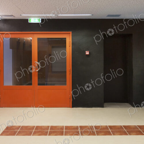 Corridor with orange entrance doors, orange and black colour scheme, tiled floor… Corridor with orange entrance doors, orange and black colour scheme, tiled floor…