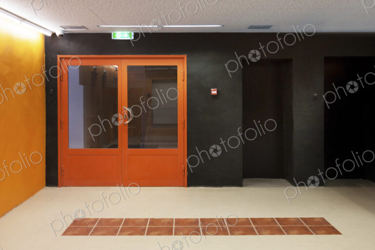 Corridor with orange entrance doors, orange and black colour scheme, tiled floor…
