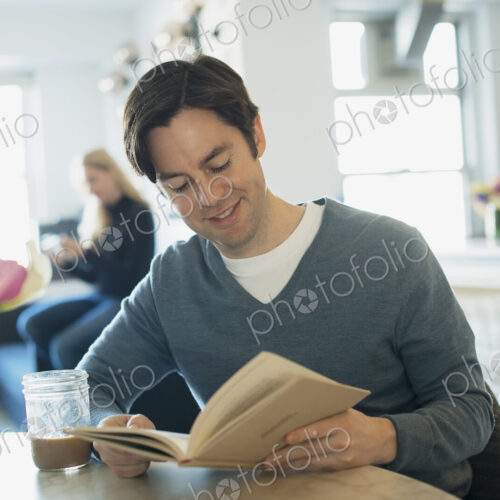 Couple Relaxing at Home, man reading, woman using smartphone Couple Relaxing at Home, man reading, woman using smartphone