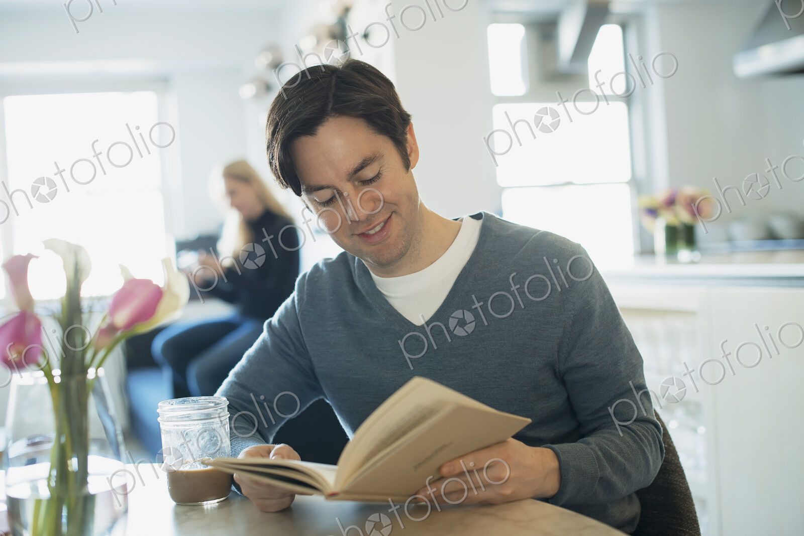 Couple Relaxing at Home, man reading, woman using smartphone