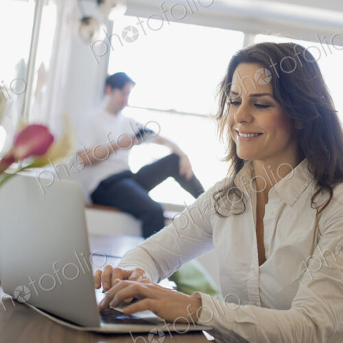 Couple at Home, Woman using Laptop and Man using Tablet Couple at Home, Woman using Laptop and Man using Tablet