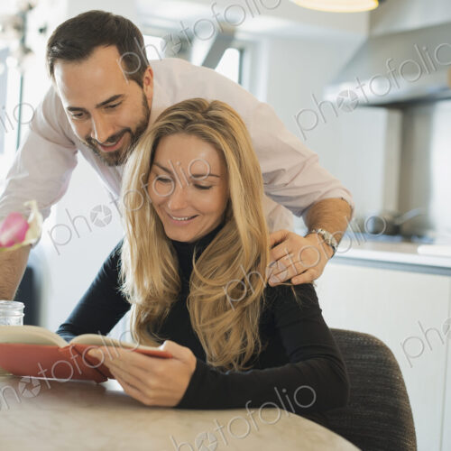 Couple at home looking at book together Couple at home looking at book together