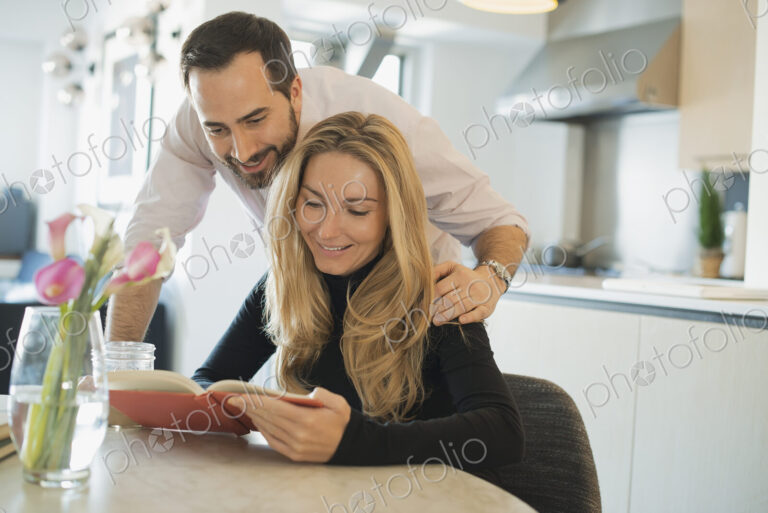 Couple at home looking at book together