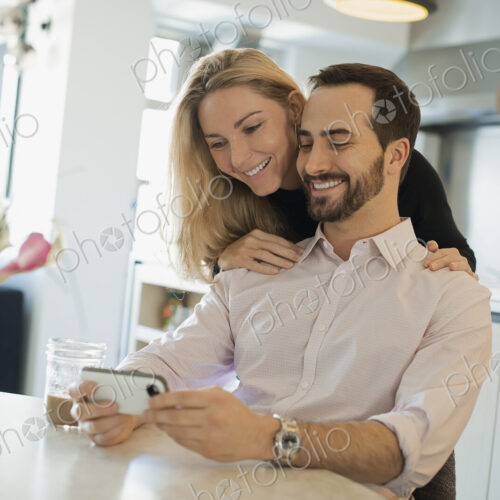 Couple at home looking at pictures on smartphone Couple at home looking at pictures on smartphone
