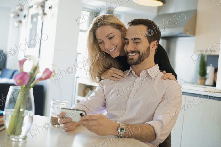 Couple at home looking at pictures on smartphone