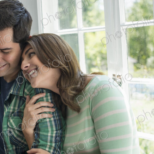 Couple embracing by a window. Couple embracing by a window.