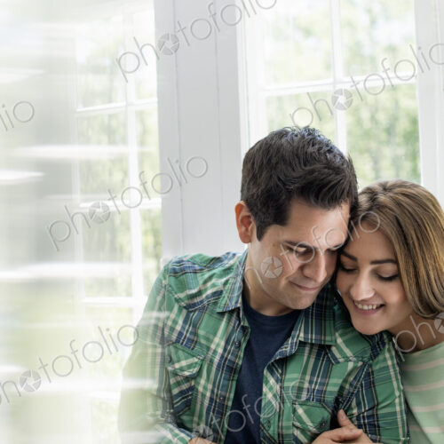 Couple embracing by a window. Couple embracing by a window.