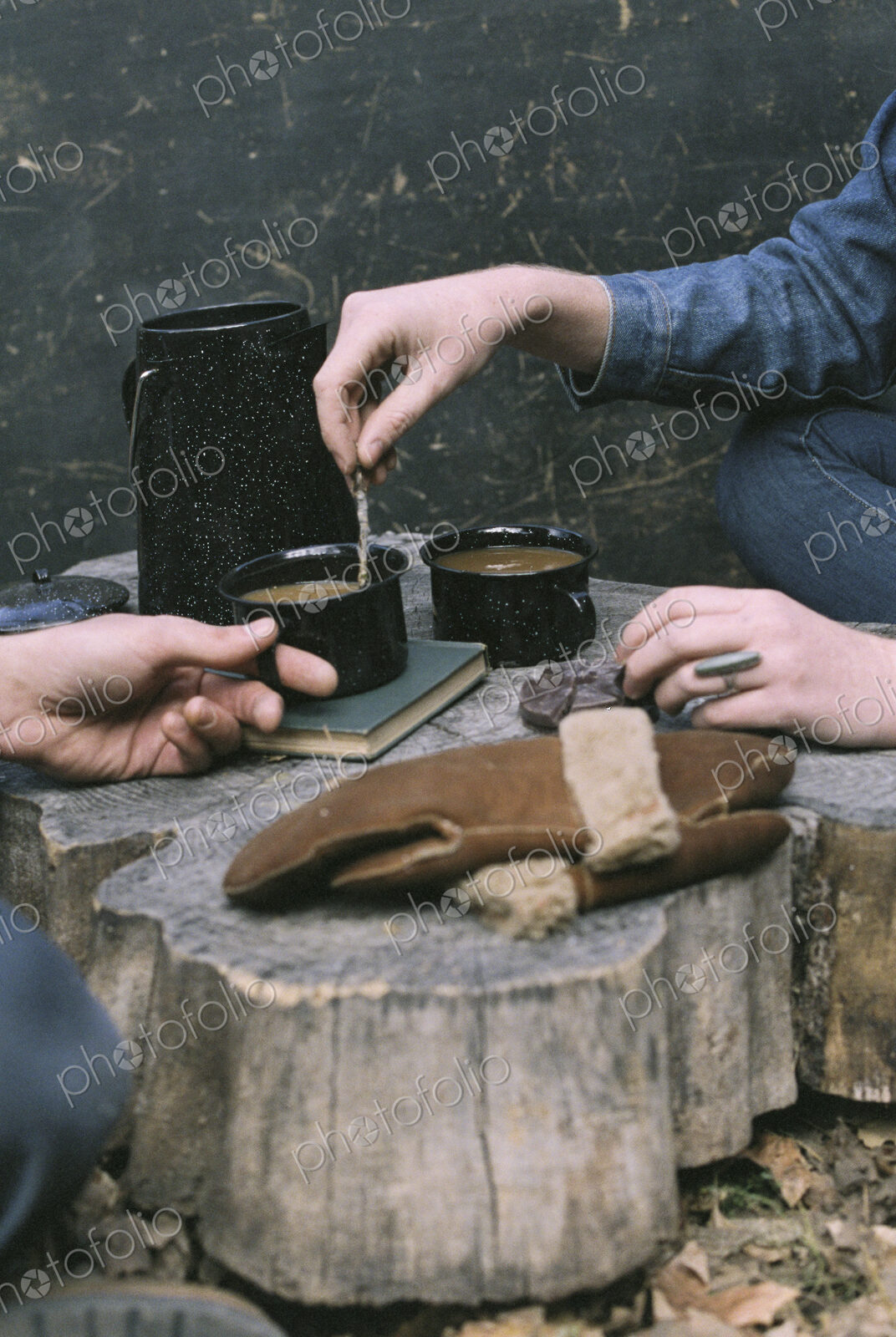 Couple having coffee in a forest, two mugs of coffee, a coffee pot and a pair of…