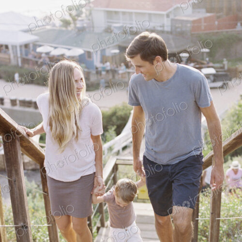 Couple holding hands with their young son, walking up a staircase.