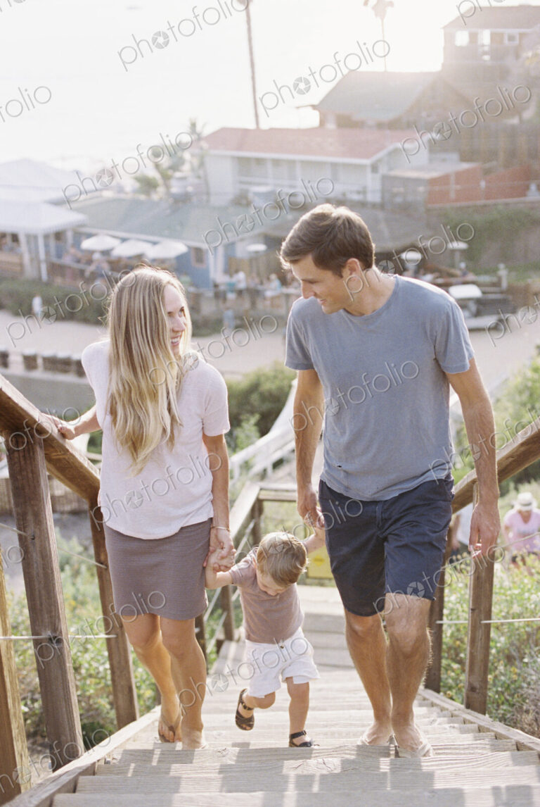 Couple holding hands with their young son, walking up a staircase.