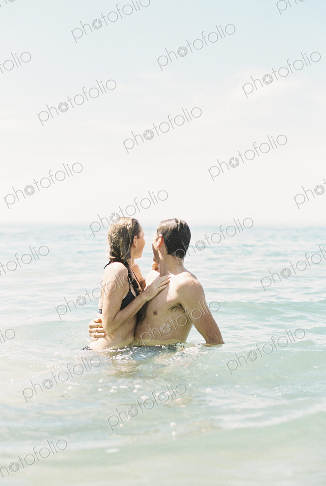 Couple hugging each other, in waist deep water.