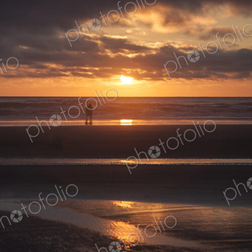 Couple hugging on Cannon Beach with dramatic cloudy sky at sunset. Couple hugging on Cannon Beach with dramatic cloudy sky at sunset.