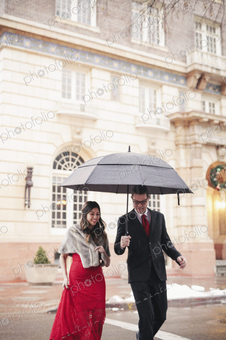 Couple in evening dress outside in wet weather in city