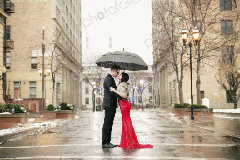 Couple in evening dress outside in wet weather in city