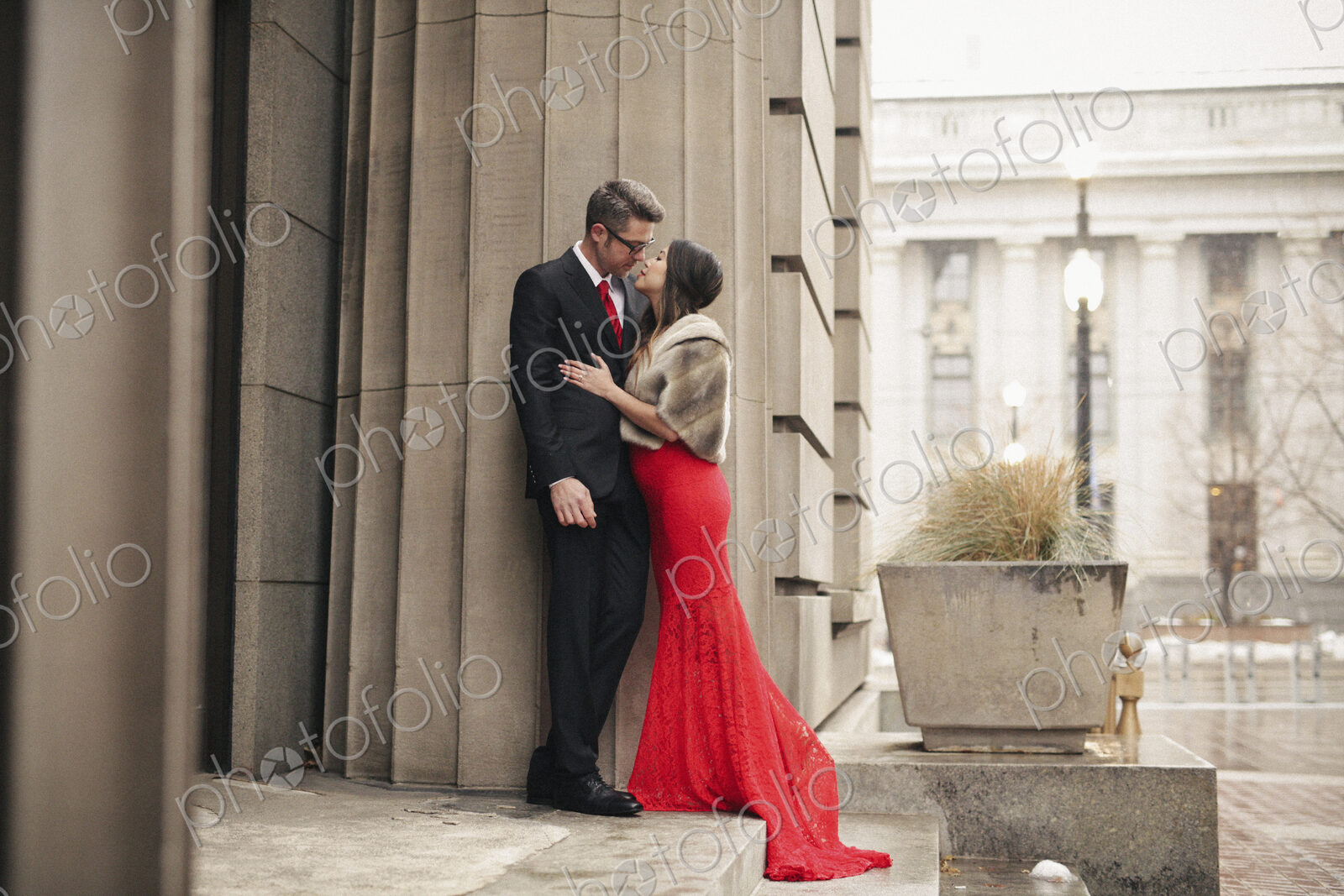 Couple in evening dress outside in wet weather in city