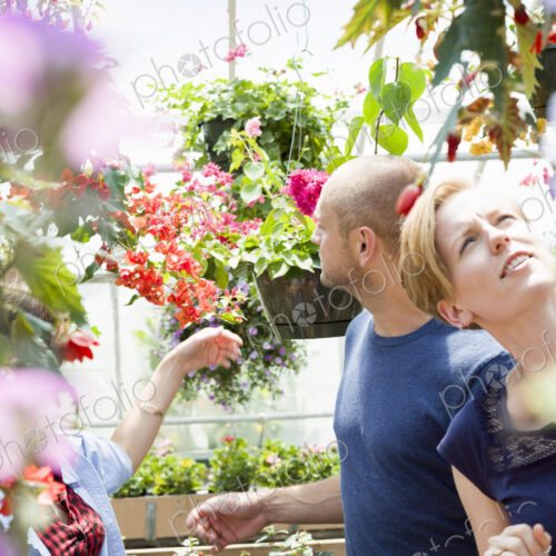 Couple looking at colourful flowers and hanging baskets in a garden centre. Couple looking at colourful flowers and hanging baskets in a garden centre.