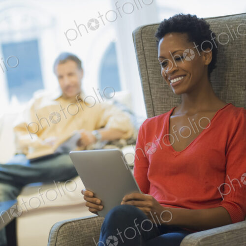 Couple relaxing at home reading, woman with tablet