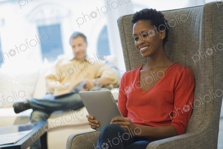 Couple relaxing at home reading, woman with tablet