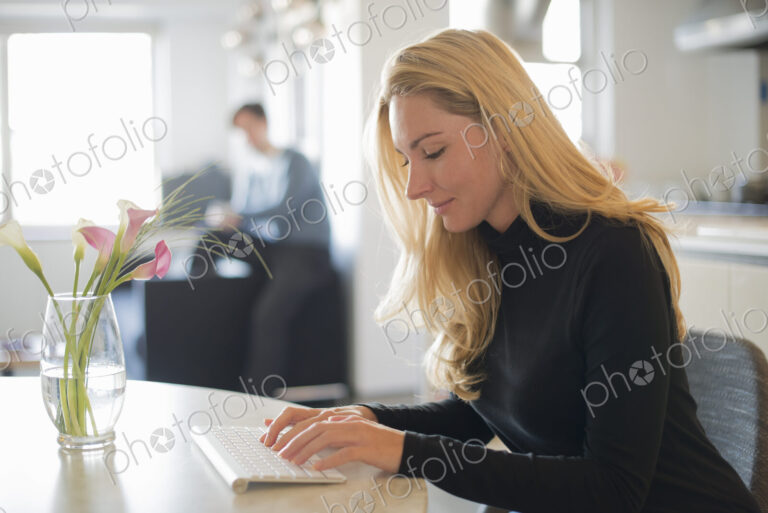 Couple relaxing at home, woman using keyboard
