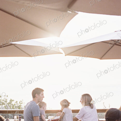Couple sitting under a parasol in a restaurant with their son and daughter. Couple sitting under a parasol in a restaurant with their son and daughter.