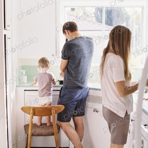 Couple standing in a kitchen, their son standing on a chair beside them. Couple standing in a kitchen, their son standing on a chair beside them.