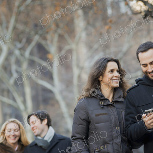 Couple walking in urban park with smartphone Couple walking in urban park with smartphone