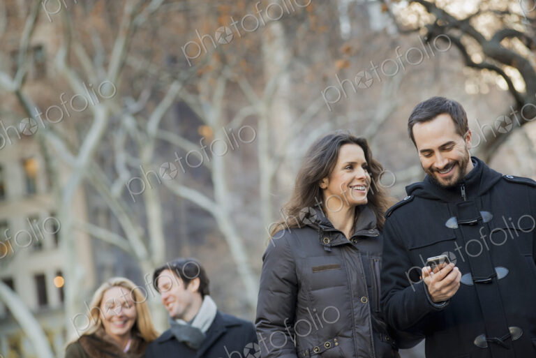 Couple walking in urban park with smartphone