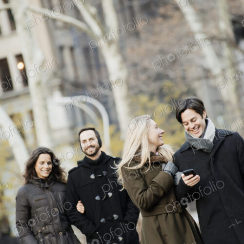 Couple walking in urban park with smartphone Couple walking in urban park with smartphone