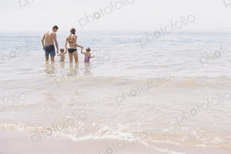Couple with their son and daughter, A family standing in shallow water off the beach.