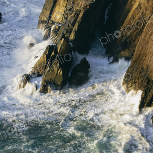 Crashing waves and surf at the base of sheer cliffs on the ocean coastline. Crashing waves and surf at the base of sheer cliffs on the ocean coastline.