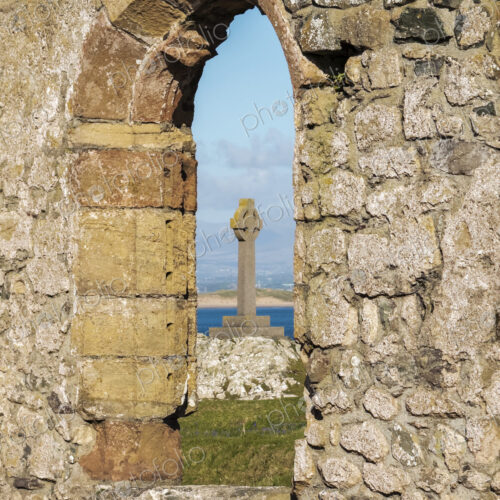 Cross of St David seen through the window arch of a ruined church, Eglwys Santes…