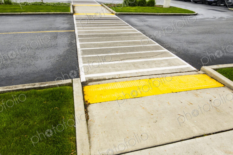Crosswalk for pedestrians on a two lane road, coloured paving and white lines on the road.