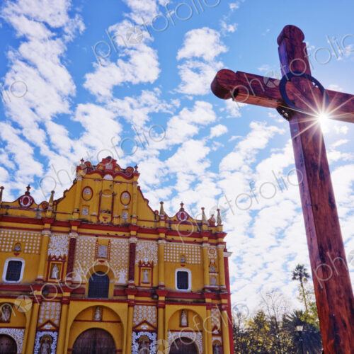Crucifix in a courtyard in front of an ornate painted church. Crucifix in a courtyard in front of an ornate painted church.