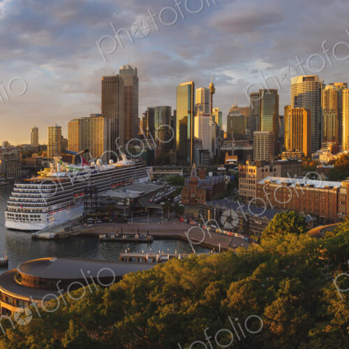 Cruise ship docked in Sydney Harbour with skyscrapers behind.