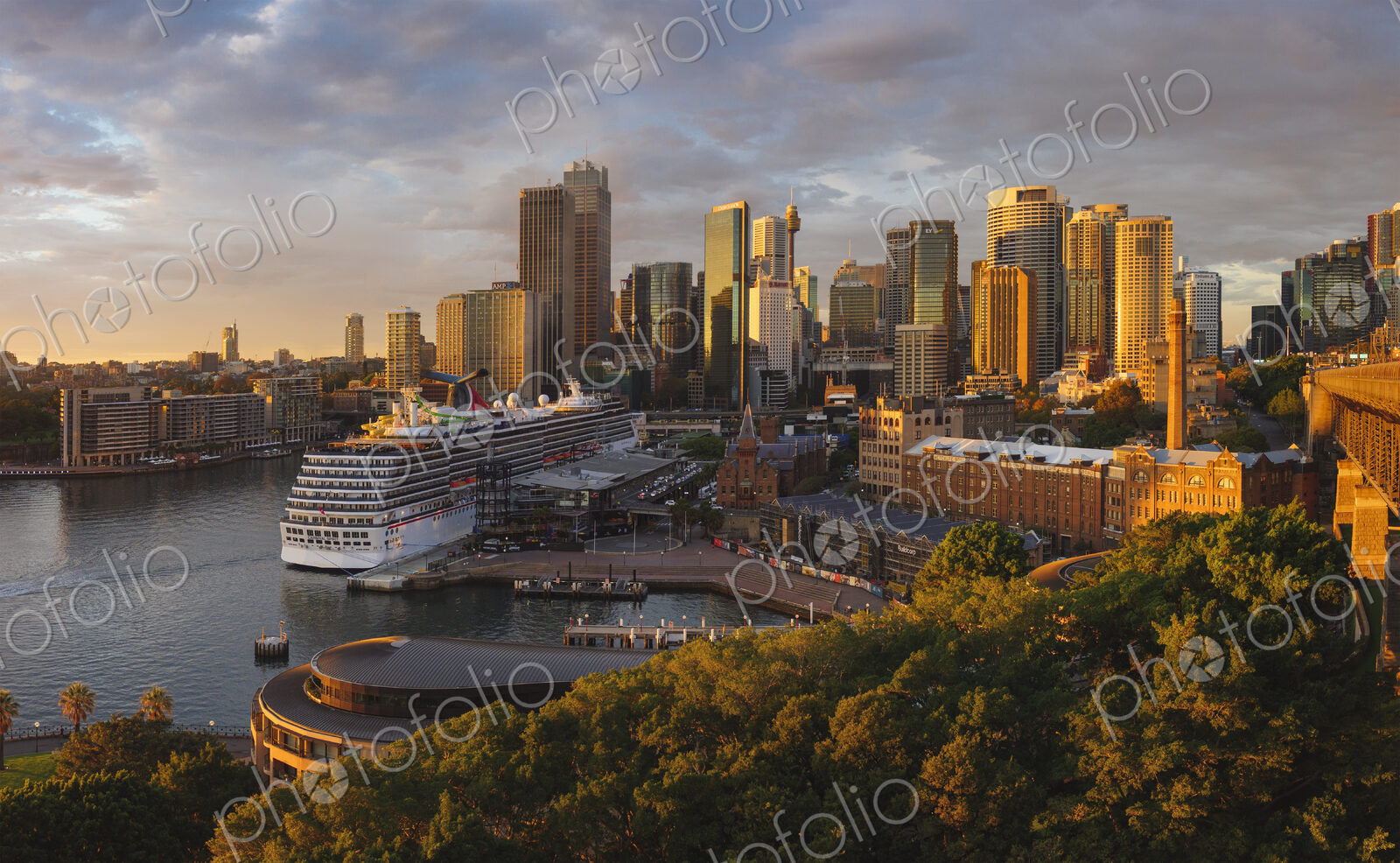 Cruise ship docked in Sydney Harbour with skyscrapers behind.