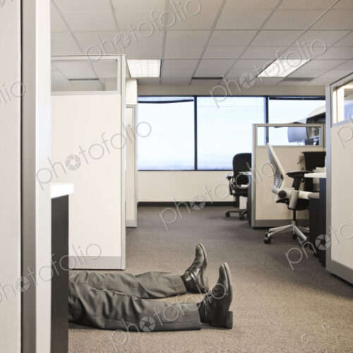 Cubicle office set up with business person laying on the floor. Cubicle office set up with business person laying on the floor.