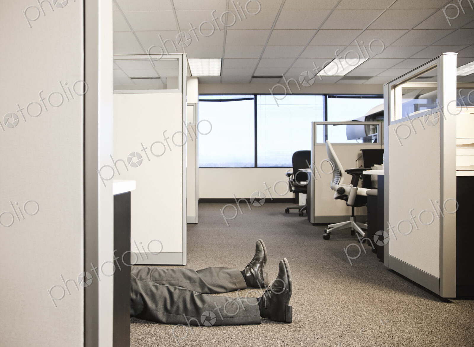 Cubicle office set up with business person laying on the floor.