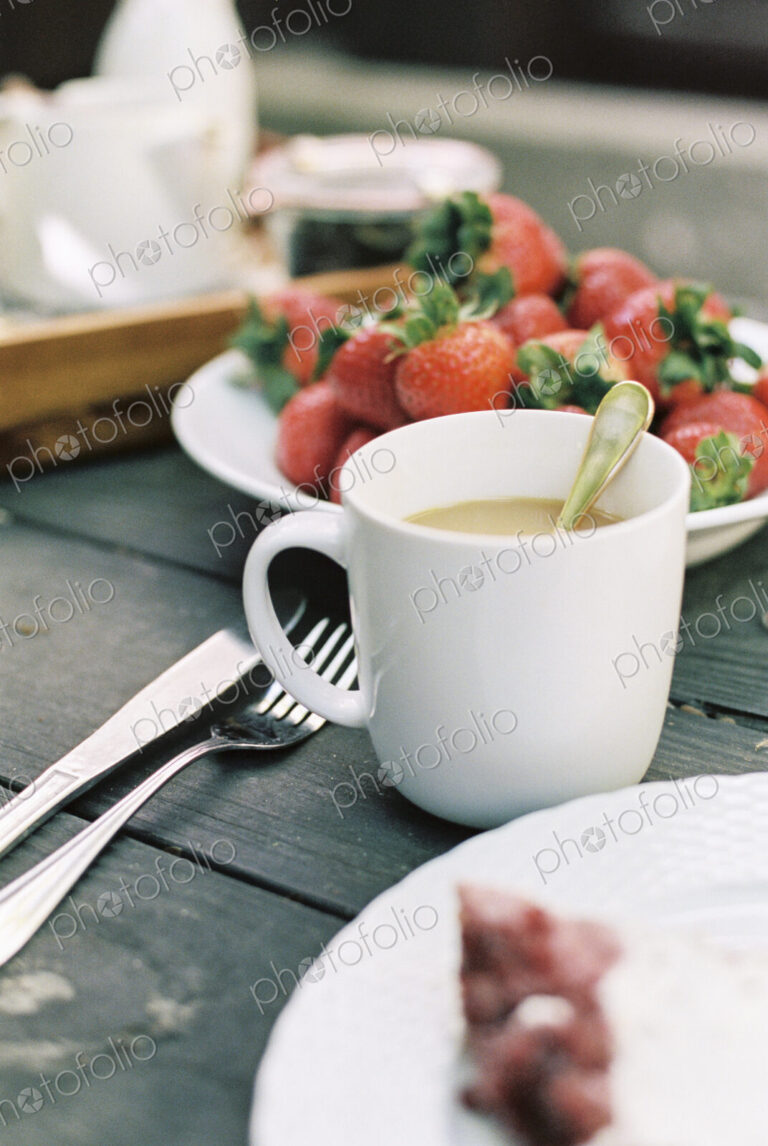 Cup of tea and plate of fresh strawberries on a table.