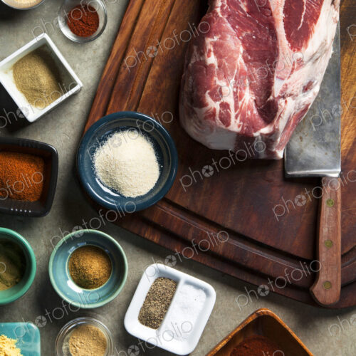 Cutting board with pork shoulder and variety of spices Cutting board with pork shoulder and variety of spices