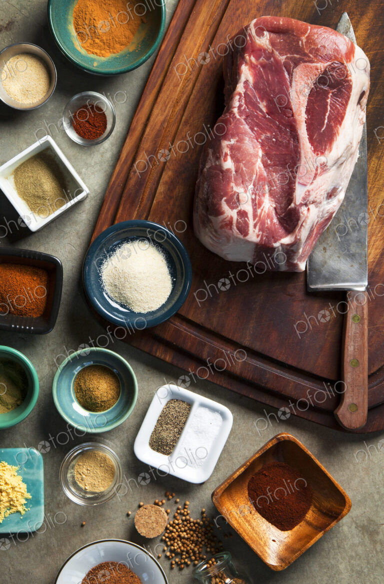Cutting board with pork shoulder and variety of spices