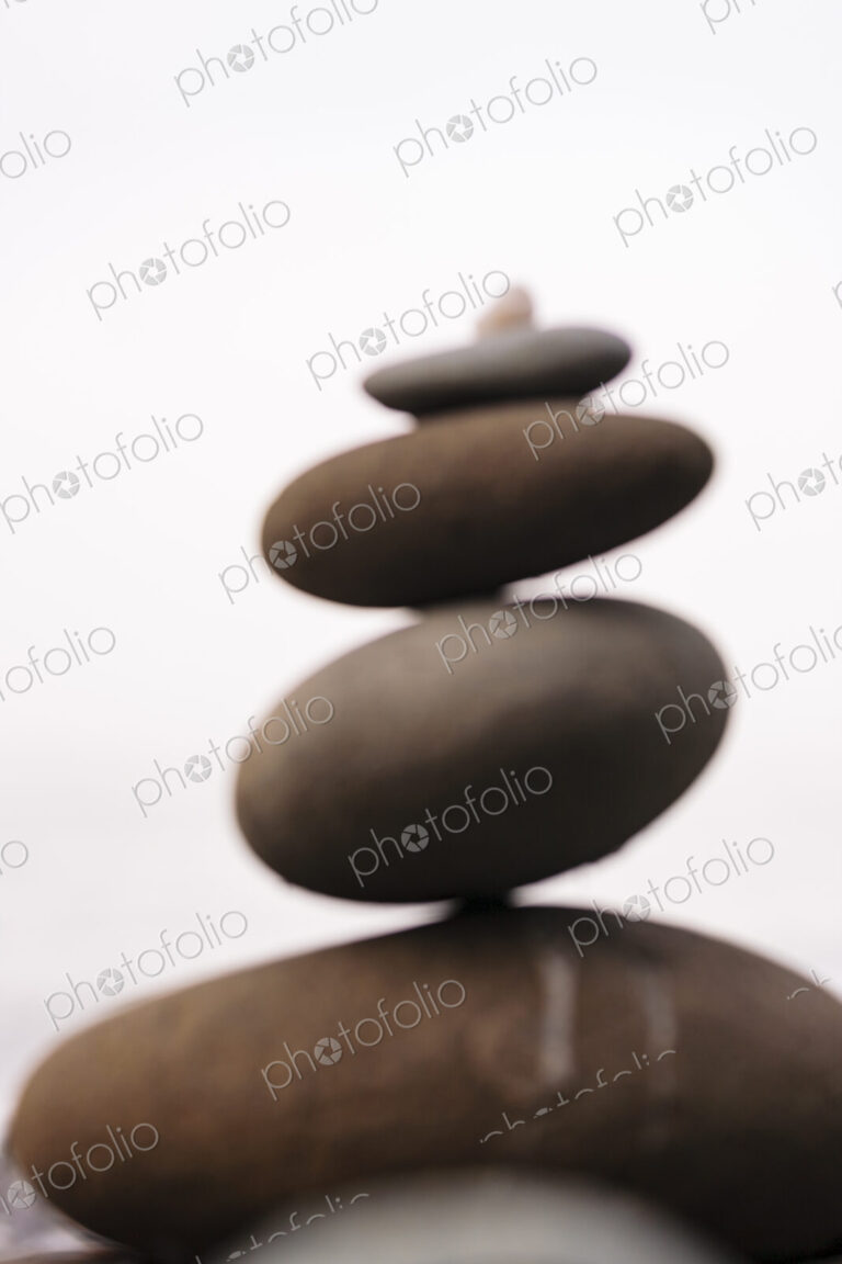 Defocussed stack of balancing stones in decreasing size on a white background.